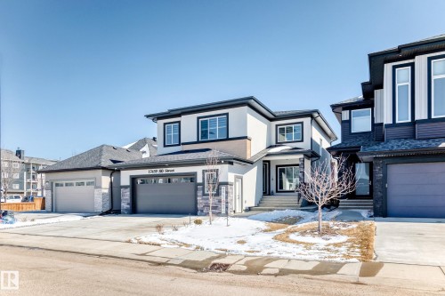 Contemporary exterior featuring a light-colored facade with dark trim, stone accents, and multiple windows - 17459 80 Street, Edmonton, AB - Outdoor With Facade