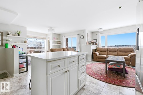 Kitchen island featuring white cabinetry with silver hardware and a light-toned countertop - 115 10105 95 Street, Edmonton, AB - Indoor Photo Showing Other Room