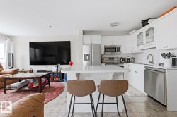 Open-concept kitchen featuring white cabinetry, stainless steel appliances, a white subway tile backsplash, and a central island with a solid surface countertop - 