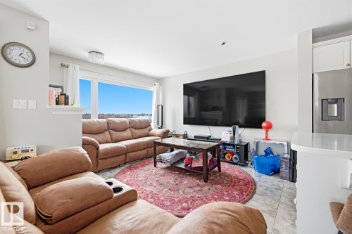 Living area featuring a large picture window, light-colored walls, recessed lighting, and tile flooring - 115 10105 95 Street, Edmonton, AB - Indoor Photo Showing Living Room