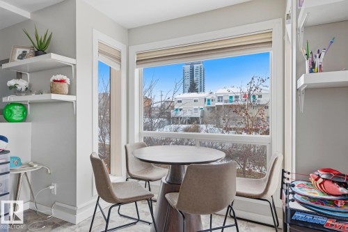 Bright dining area featuring corner windows with white trim and roll-down blinds - 115 10105 95 Street, Edmonton, AB - Indoor