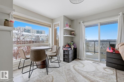 Bright living area featuring expansive windows and a sliding glass door leading to a balcony - 115 10105 95 Street, Edmonton, AB - Indoor