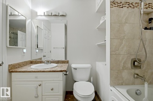 Bathroom featuring a white vanity with an undermount sink, a granite-look countertop, and a tiled backsplash - 115 10105 95 Street, Edmonton, AB - Indoor Photo Showing Bathroom