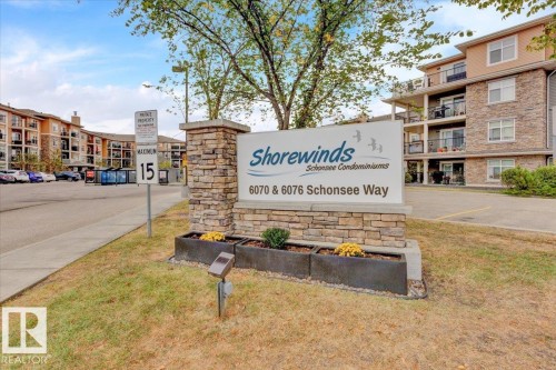 Shorewinds Schoonsee Condominiums entry sign with a stone facade, integrated planters, and established landscaping - 326 6076 Schonsee Way, Edmonton, AB - Outdoor
