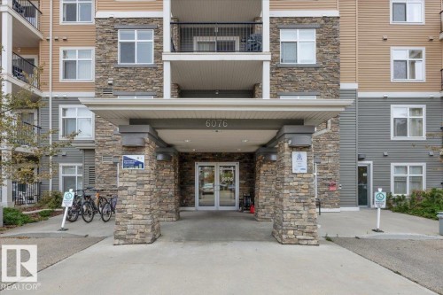 Building exterior featuring a stone and siding facade with multiple balconies and a covered entrance - 326 6076 Schonsee Way, Edmonton, AB - Outdoor With Balcony With Facade
