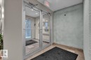 Glass double doors with aluminum frames, recessed ceiling lighting, and a prominent "EXIT" sign above - 326 6076 Schonsee Way, Edmonton, AB  - Indoor Photo Showing Other Room 
