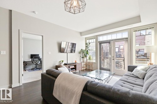 Living area featuring dark flooring, light-colored walls, and a contemporary ceiling light fixture - 406 10811 72 Avenue, Edmonton, AB - Indoor Photo Showing Living Room