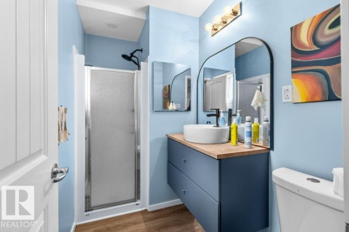 Contemporary bathroom with a floating vanity featuring a vessel sink, wood-finish countertop, and black fixtures - 12207 110 Avenue, Edmonton, AB - Indoor Photo Showing Bathroom