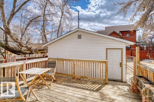 Spacious wooden deck featuring a white paneled outbuilding with a gable roof, privacy fencing, and mature trees - 12207 110 Avenue, Edmonton, AB - Outdoor With Deck Patio Veranda With Exterior