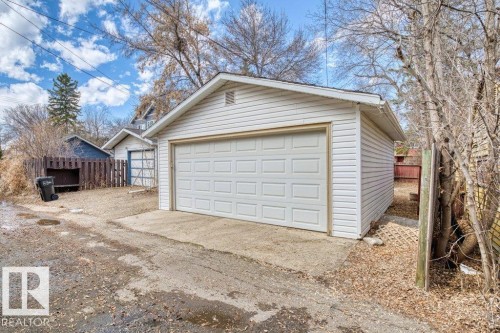 Detached garage featuring a paneled overhead door and white vinyl siding - 12207 110 Avenue, Edmonton, AB - Outdoor