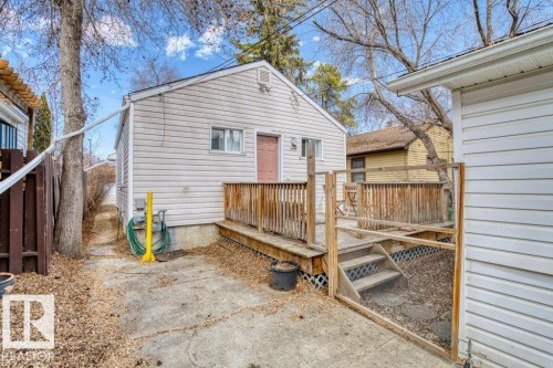 Rear exterior featuring light-colored siding, a brown door, and a multi-level wood deck with steps - 12207 110 Avenue, Edmonton, AB - Outdoor With Exterior