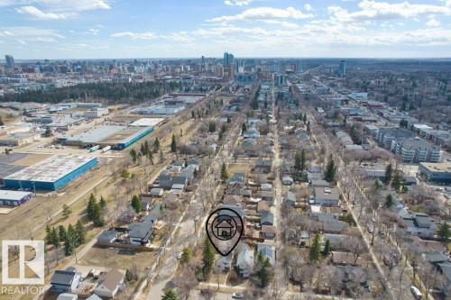 Residential area featuring mature trees and street-lined properties, with commercial buildings and a city skyline visible in the distance - 12207 110 Avenue, Edmonton, AB - Outdoor With View