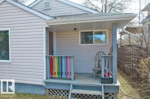 Covered front porch featuring pastel siding, a white-framed window, and a colorful railing - 12207 110 Avenue, Edmonton, AB - Outdoor With Exterior