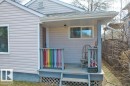 Covered front porch featuring pastel siding, a white-framed window, and a colorful railing - 12207 110 Avenue, Edmonton, AB  - Outdoor With Exterior 