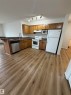 Kitchen area featuring wood-finish flooring, a breakfast bar, wood cabinetry, white appliances, and track lighting - 104 8119 112 Avenue Nw, Edmonton, AB  - Indoor Photo Showing Kitchen 