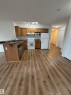 Kitchen featuring wood-finish cabinetry, dark countertops, and a breakfast bar - 104 8119 112 Avenue Nw, Edmonton, AB  - Indoor Photo Showing Kitchen With Double Sink 