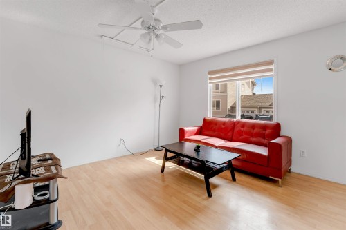 Living area featuring wood-finish flooring, a ceiling fan, and a large window with blinds - 48 2503 24 Street, Edmonton, AB - Indoor Photo Showing Other Room