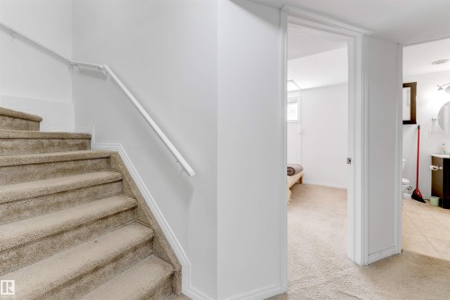 Carpeted staircase with white handrail and baseboards - 48 2503 24 Street, Edmonton, AB - Indoor Photo Showing Other Room
