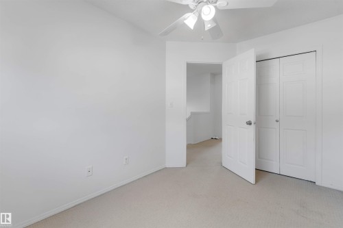 Neutral-toned carpet flooring and white walls with a ceiling fan light fixture - 48 2503 24 Street, Edmonton, AB - Indoor Photo Showing Other Room