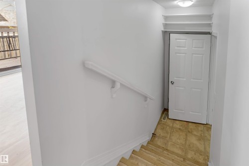 Stairwell with light wood-finish treads, white painted walls, and a white handrail - 48 2503 24 Street, Edmonton, AB - Indoor Photo Showing Other Room