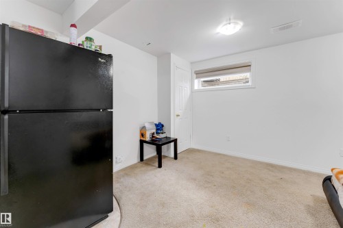 Room featuring neutral carpeting, white painted walls, a flush-mount ceiling light, and a window with a roller shade - 48 2503 24 Street, Edmonton, AB - Indoor Photo Showing Other Room