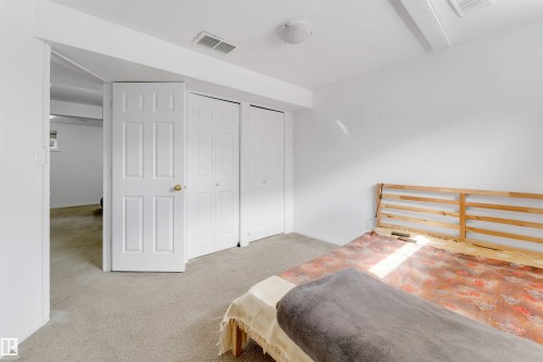 Room featuring neutral carpeting, white walls, two paneled doors, two bi-fold closet doors, and recessed lighting - 48 2503 24 Street, Edmonton, AB - Indoor Photo Showing Bedroom