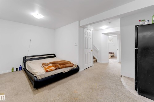 Carpeted room with white walls, overhead ceiling light fixture, and a segmented doorway leading to a staircase and additional interior space - 48 2503 24 Street, Edmonton, AB - Indoor Photo Showing Bedroom