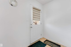 Entry door with lower glass panel and horizontal blinds, set against light-colored walls and wood-finish flooring - 