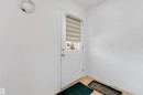 Entry door with lower glass panel and horizontal blinds, set against light-colored walls and wood-finish flooring - 48 2503 24 Street, Edmonton, AB  - Indoor Photo Showing Other Room 