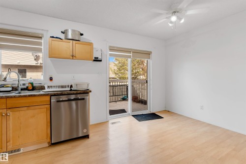 Kitchen with wood-finish flooring, light wood cabinetry, and stainless steel dishwasher - 48 2503 24 Street, Edmonton, AB - Indoor Photo Showing Kitchen With Double Sink