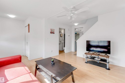 Open-concept living area featuring wood-finish flooring, a ceiling fan with integrated lighting, and flush-mount lighting fixtures - 48 2503 24 Street, Edmonton, AB - Indoor Photo Showing Living Room