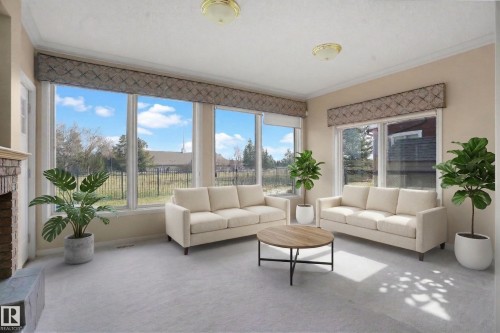 This room features extensive windows with valances, light-colored carpeting, and a fireplace with a stone facade - 10815 Bearspaw Dr E Nw, Edmonton, AB - Indoor Photo Showing Living Room