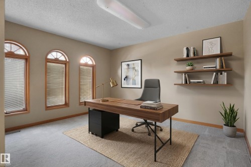 The room features three arched windows with wooden frames and blinds, creating a bright and inviting atmosphere - 10815 Bearspaw Dr E Nw, Edmonton, AB - Indoor Photo Showing Office