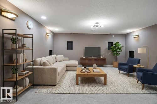 Spacious living area featuring recessed lighting, wall sconces, and a textured area rug - 10815 Bearspaw Dr E Nw, Edmonton, AB - Indoor