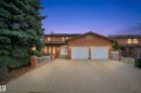 The property features a brick exterior, a driveway, a two-car garage with white doors, and arched windows - 10815 Bearspaw Dr E Nw, Edmonton, AB  - Outdoor 