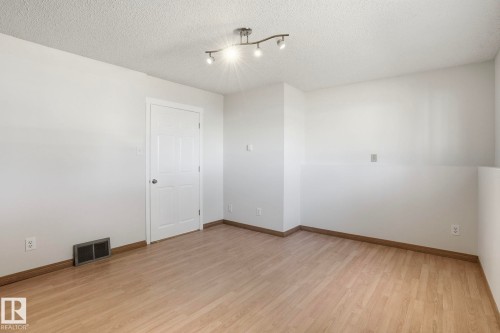 Light wood-finish flooring complemented by white walls - 15811 114 Street, Edmonton, AB - Indoor Photo Showing Other Room