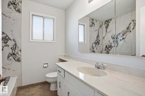 Bathroom featuring a white vanity with an integrated sink, polished chrome faucet, and white cabinetry with dark hardware - 15811 114 Street, Edmonton, AB - Indoor Photo Showing Bathroom