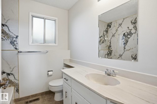 Bathroom featuring a white vanity with an integrated sink, polished chrome faucet, and a large wall-mounted mirror - 15811 114 Street, Edmonton, AB - Indoor Photo Showing Bathroom