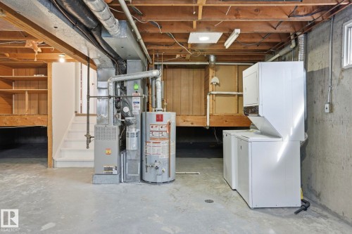 Lower level utility space featuring a water heater, furnace, and a stacked washer and dryer - 15811 114 Street, Edmonton, AB - Indoor Photo Showing Basement