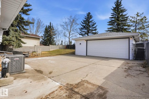 Detached garage with a paneled garage door, exterior wall lighting, and shingle roofing - 15811 114 Street, Edmonton, AB - Outdoor