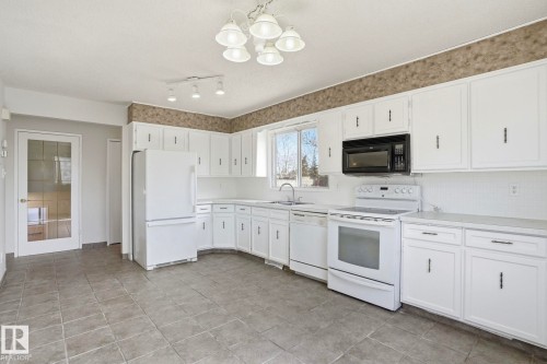 Kitchen featuring white cabinetry, a built-in black microwave, a white electric range, and a white dishwasher - 15811 114 Street, Edmonton, AB - Indoor Photo Showing Kitchen
