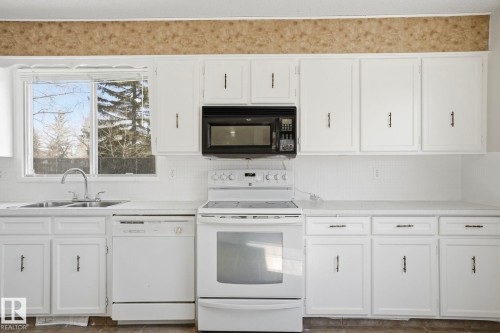 Kitchen featuring white cabinetry, white appliances, a double basin sink, and an over-the-range microwave - 15811 114 Street, Edmonton, AB - Indoor Photo Showing Kitchen With Double Sink