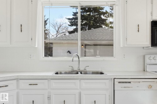 Double basin stainless steel sink with a chrome faucet set against white cabinetry and countertops - 15811 114 Street, Edmonton, AB - Indoor Photo Showing Kitchen With Double Sink