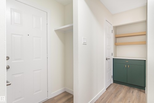 Entryway featuring wood-finish flooring, a white paneled door, and built-in shelving - 15C Callingwood Crest, Edmonton, AB - Indoor Photo Showing Other Room