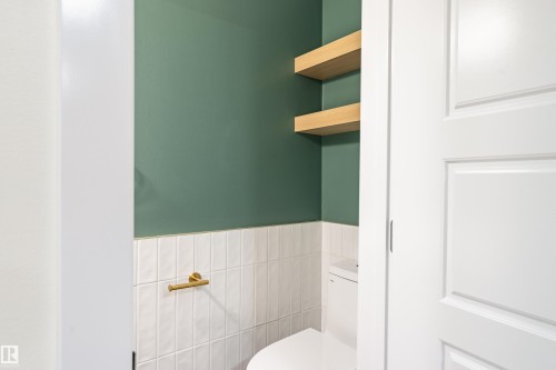 Powder room featuring a two-piece toilet, white vertical tile wainscoting, and emerald green painted walls - 15C Callingwood Crest, Edmonton, AB - Indoor Photo Showing Bathroom