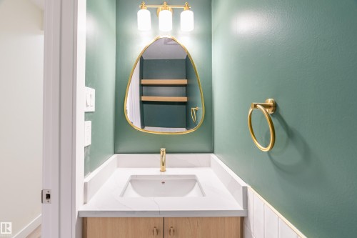 Vanity with a white countertop and integrated sink, complemented by a wood-finish cabinet base - 15C Callingwood Crest, Edmonton, AB - Indoor Photo Showing Bathroom