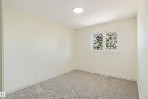 Neutral-toned room featuring a single window with white trim, light-colored walls, gray carpet flooring, and a flush-mount ceiling light fixture - 15C Callingwood Crest, Edmonton, AB - Indoor Photo Showing Other Room