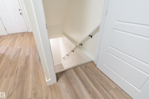 Light wood-finish flooring extending from a white paneled door into a transition area - 15C Callingwood Crest, Edmonton, AB - Indoor Photo Showing Other Room