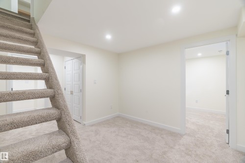 Carpeted staircase and living area with recessed lighting, light-colored walls, and white trim - 15C Callingwood Crest, Edmonton, AB - Indoor Photo Showing Other Room