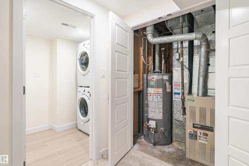 Dedicated utility area featuring a stacked washer and dryer, adjacent to a closet housing the water heater and HVAC system - 15C Callingwood Crest, Edmonton, AB - Indoor Photo Showing Laundry Room